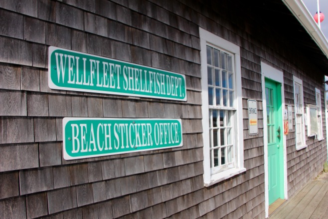 The sign of the Wellfleet Shellfish Department. The building sits by the beginning of the pier at Wellfleet Harbor and next to Mac’s On the Pier.